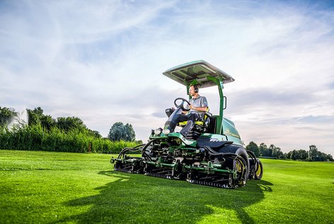 Greenkeeper sitzt auf großem Rasenmäher