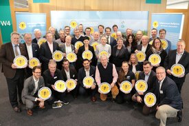 Gruppenfoto mit Golfclubvertretern, die gelbes Lebensraumgolfplatz Schild hoch halten