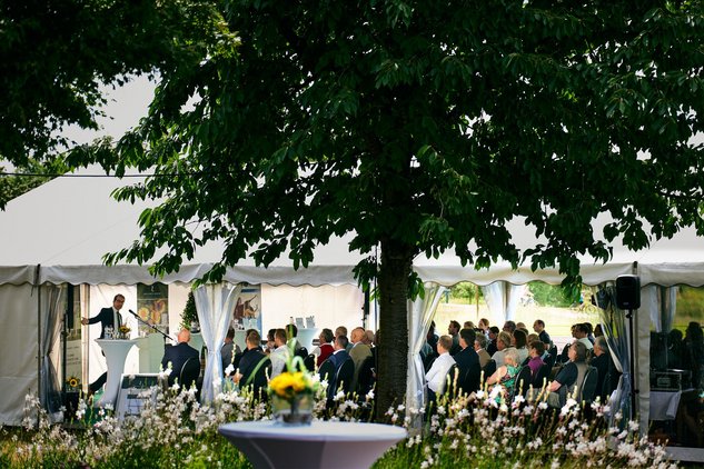 Blick von außen auf Zelt, in dem Gäste sitzen