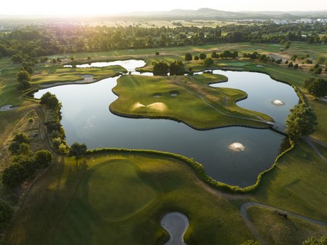 Luftaufnahme Inselgrün von Wasser umgeben bei Sonnenuntergang