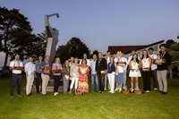 Gruppenbild mit 25 Personen auf grüner Wiese