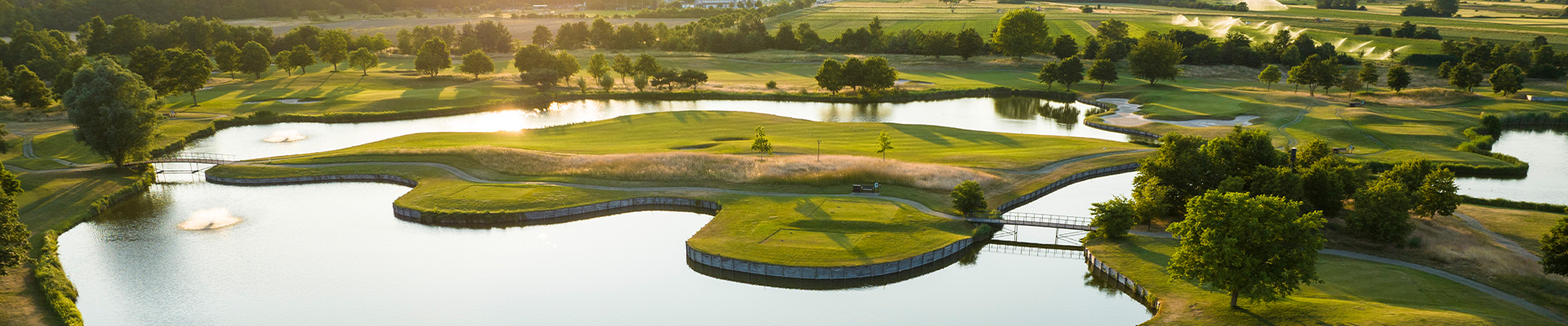 Lufaufnahme von Golfabschlägen umgeben von Wasser