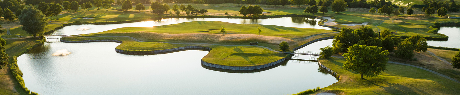 Lufaufnahme von Golfabschlägen umgeben von Wasser