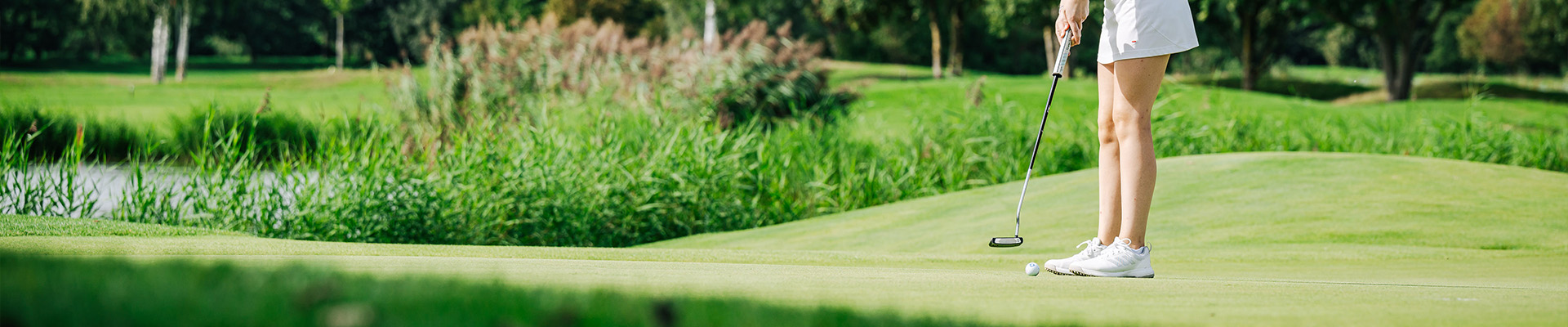 Golfer beim Abschlag mit Teich im Hintergrund